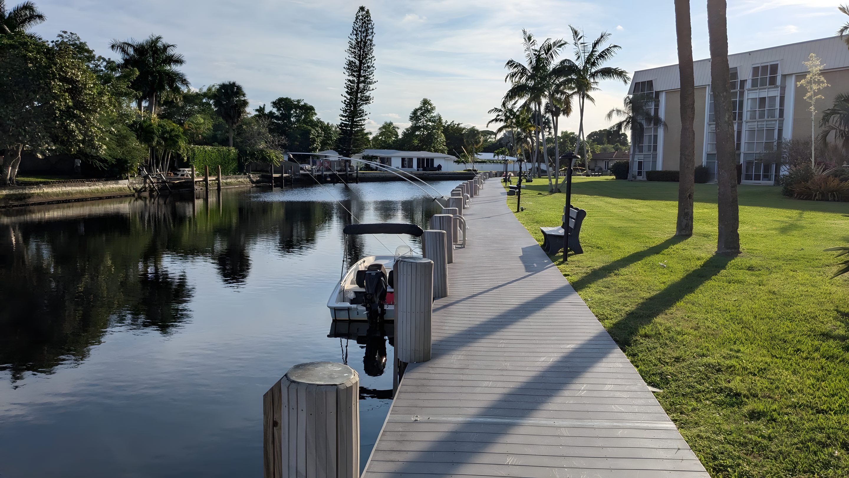 The boardwalk along the Middle River with boats moored on one side and lawn on the other.