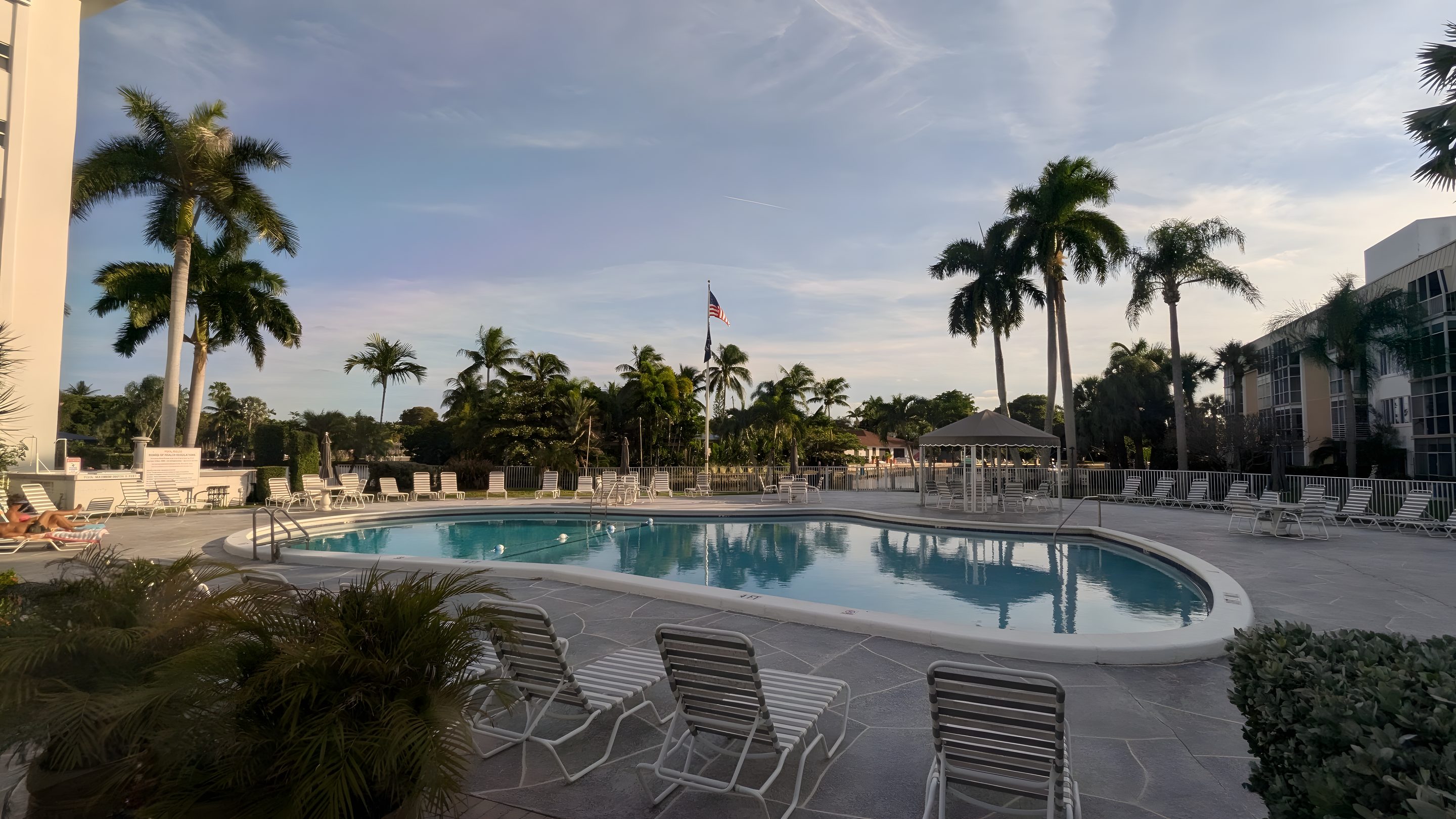 The heated pool at the Middle River Club at dusk, palms and loungers around it.